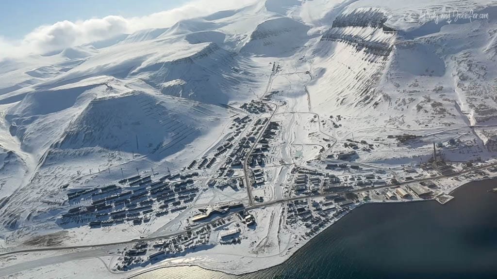 Snow-covered town in Arctic fjord with mountain backdrop