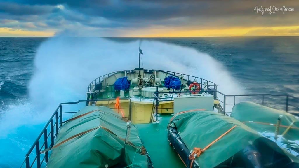 Ship bow cutting through rough Arctic waves at sunset
