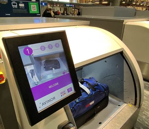 Airport self-service baggage drop kiosk with screen.