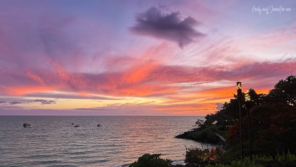 Vibrant ocean sunset with boats and tiki torch