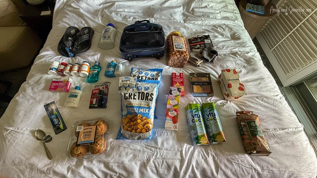 Travel essentials and snacks laid out on hotel bed