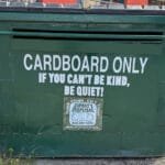 Cardboard dumpster with "Be Kind or Be Quiet" message