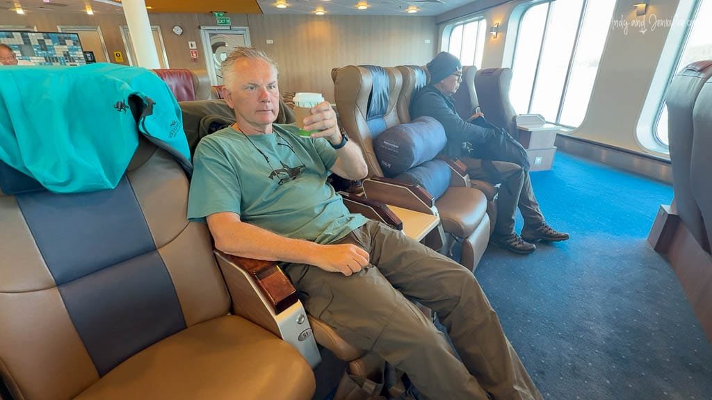 Man relaxing with coffee in ferry lounge seat.