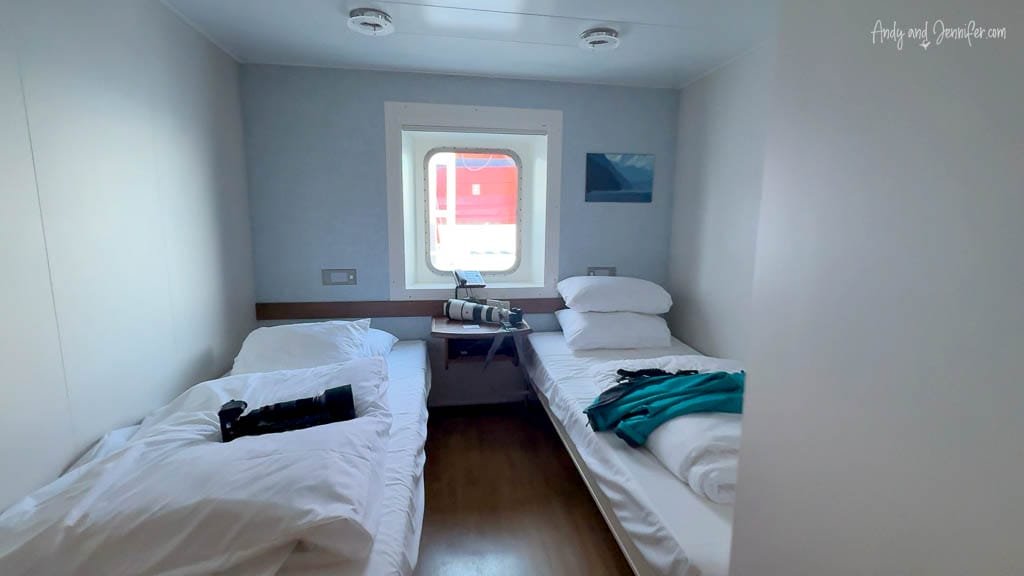 Compact ferry cabin with twin beds and window.