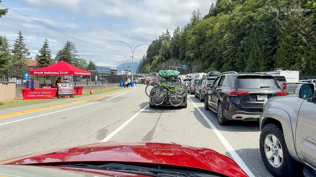 Cars lined up at ferry terminal with fruit stand