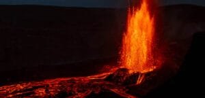 Lava fountain erupting at night with glowing flow