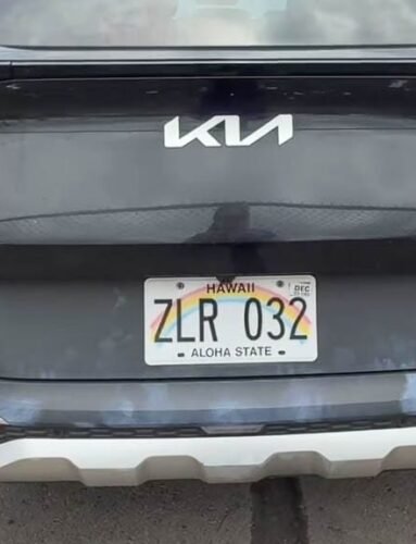 Rear view of dirty black Kia Sportage with Hawaii plate