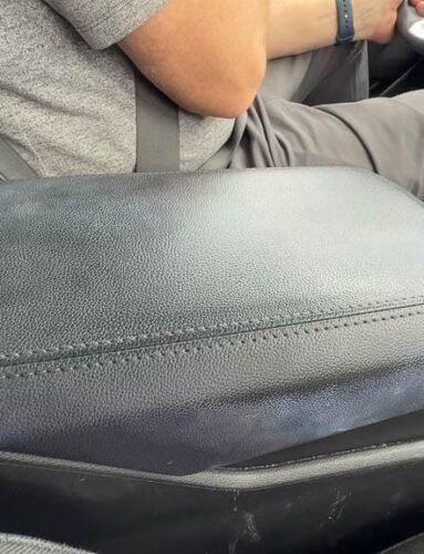 Man driving Kia with arm on dirty black center console