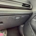 Passenger foot near dirty glove box in Kia SUV