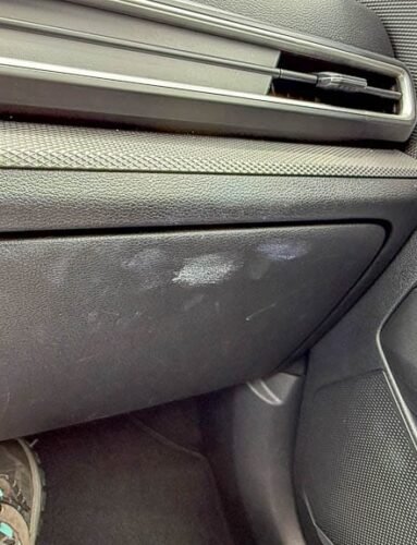Passenger foot near dirty glove box in Kia SUV