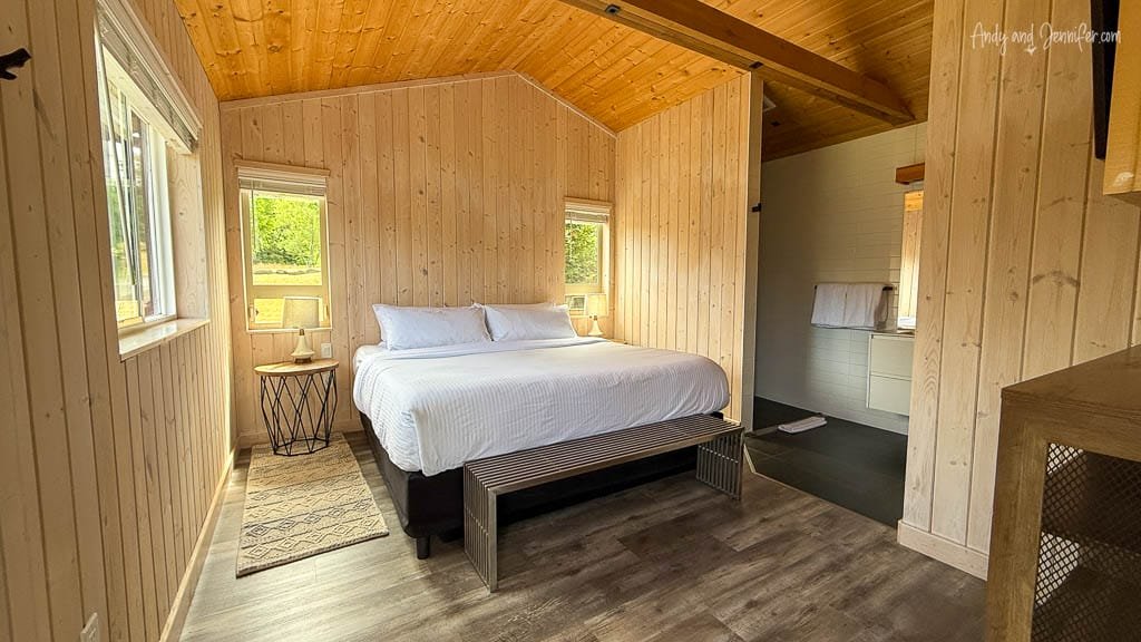 Bedroom with white linens in wood-paneled cabin