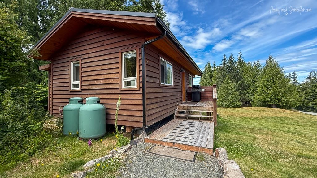 Exterior of rustic wood cabin surrounded by trees and grass