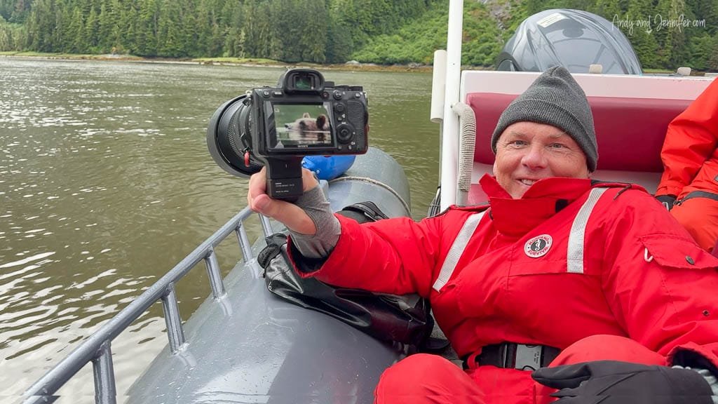 Smiling man in red suit holding camera on boat tour.