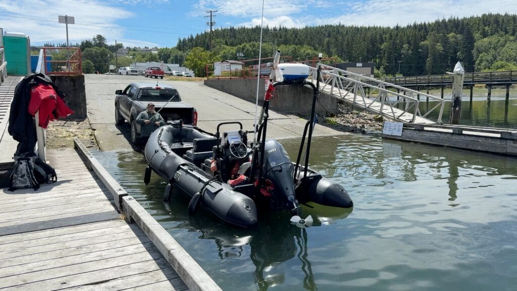 Inflatable boat being launched at marina ramp from a pickup truck on a sunny day