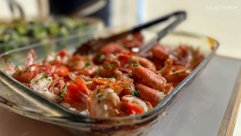 Glass dish of cooked shrimp garnished with herbs