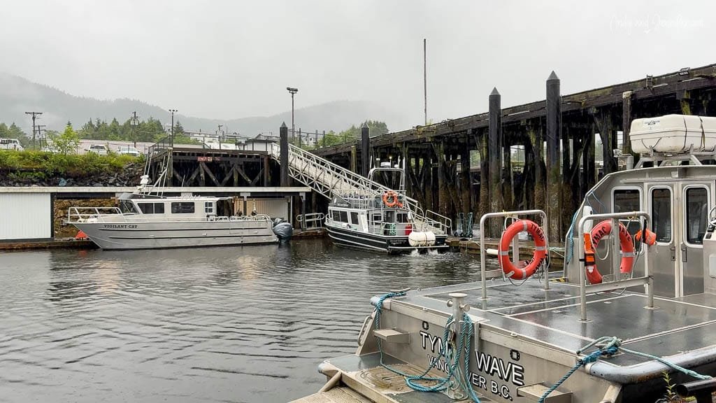 Docked boats in rainy harbor with wooden pier.