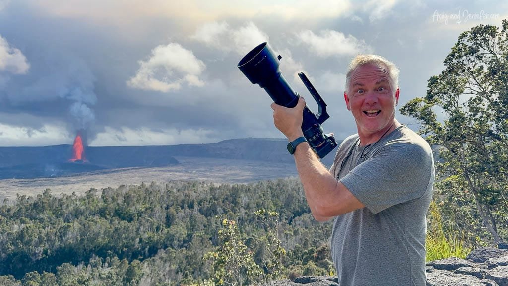 Man excitedly holding camera near erupting volcano