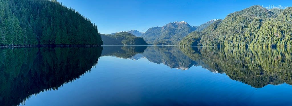 Calm coastal inlet with clear reflection and forested shores.