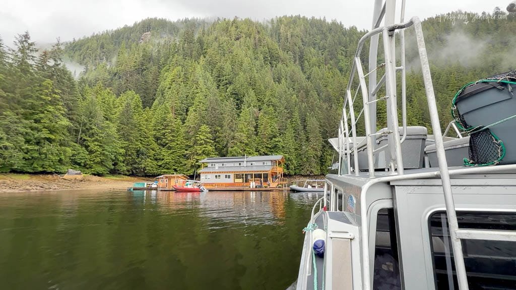 Boat approaching remote lodge in forested bay.