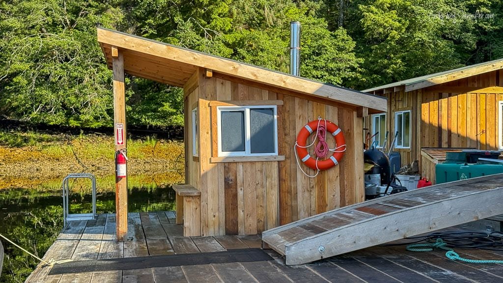 Small wooden sauna cabin on dock by forested shore