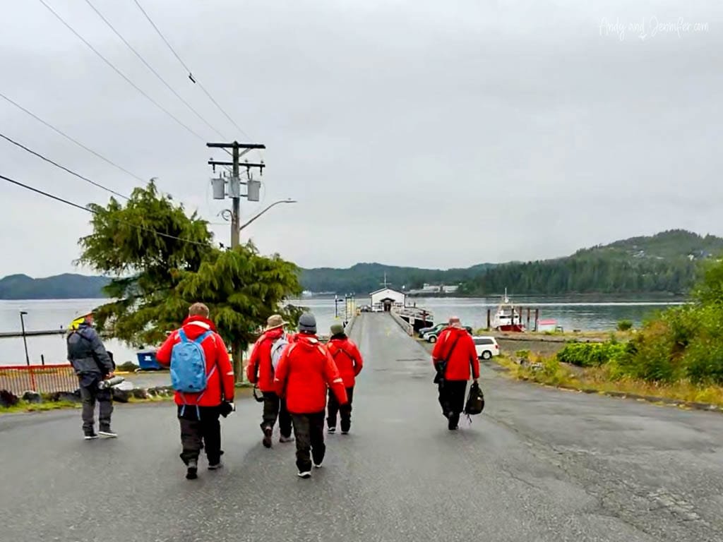 Group of people in red survival suits walking toward a dock on a cloudy day