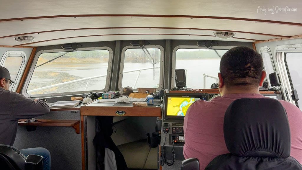 Boat interior with two men navigating in rainy weather.