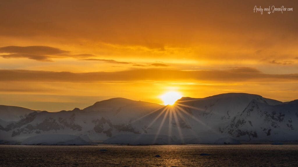 Sunrise over snowy Antarctic mountains and calm polar waters near the Lemaire Channel in Antarctica