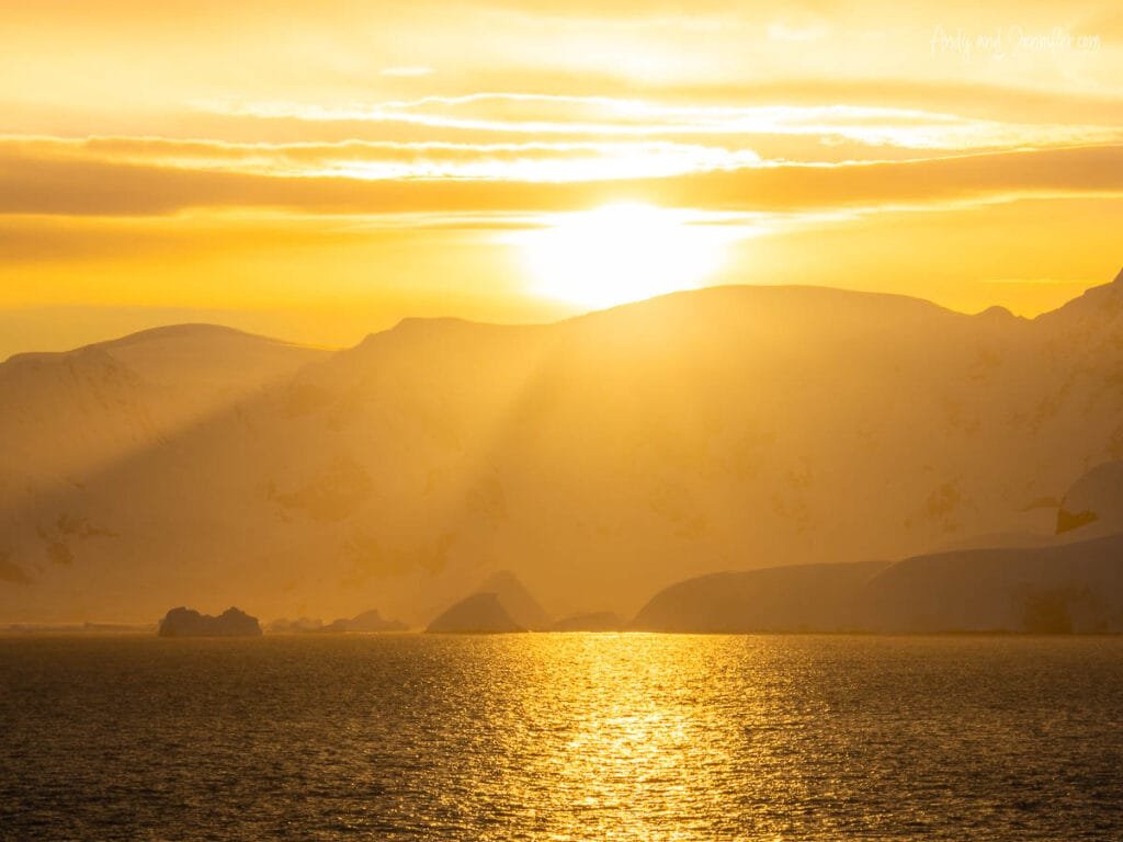 Golden Antarctic sunrise reflecting across calm ocean waters near the Antarctic Peninsula