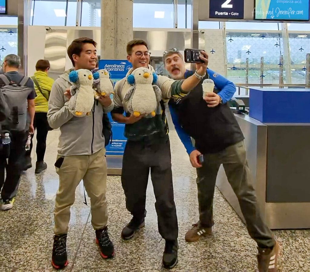 Travelers taking selfie with penguin plush toys at airport before Antarctica flight