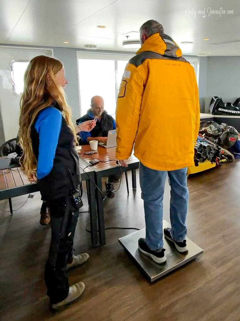 Passenger standing on scale during helicopter weight check on Antarctica expedition