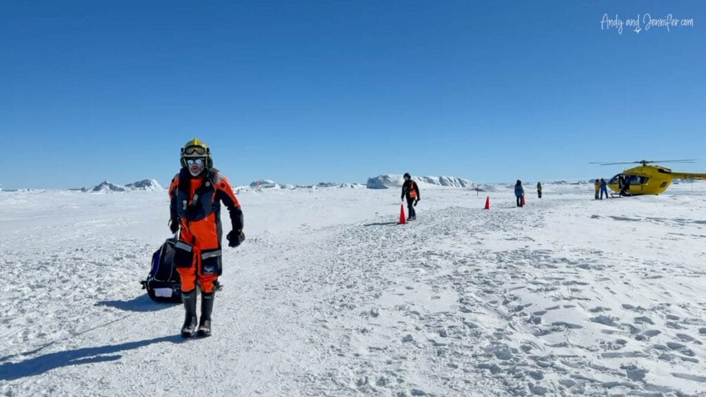 People walking across Antarctic sea ice with gear after helicopter landing