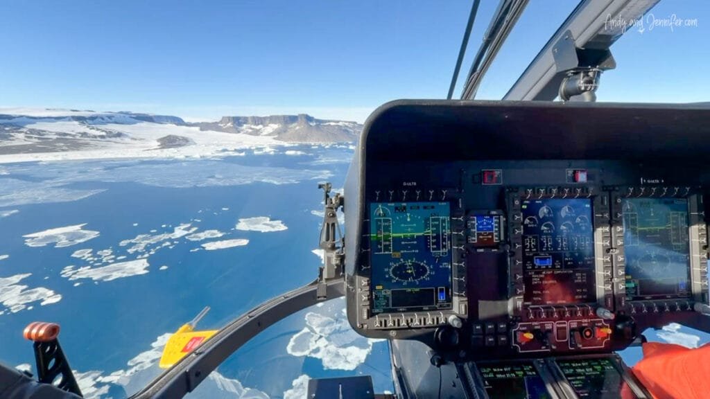 Instrument panel view from helicopter flying above ice and coastline in Antarctica