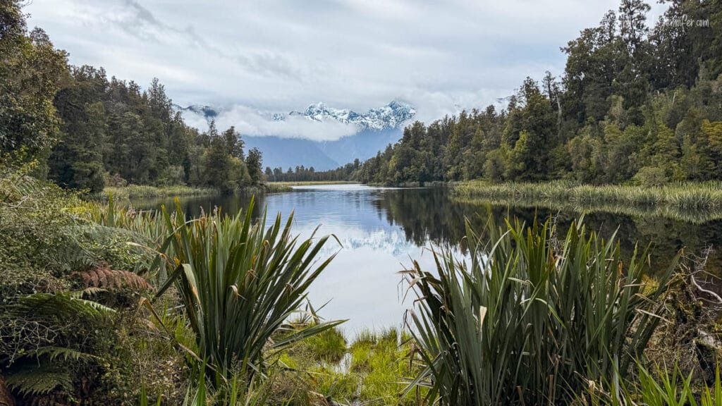 Calm lake reflecting mountains on the West Coast, South Island, New Zealand