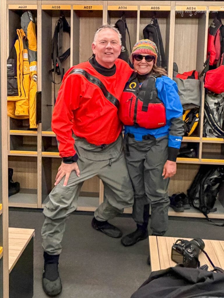 Two expedition passengers wearing dry suits and life vests preparing for stand up paddleboarding in Antarctica aboard an Antarctic expedition ship near Tower Island