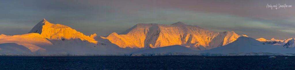 Early morning sunlight illuminating snow-covered Antarctic peaks near the Lemaire Channel in Antarctica