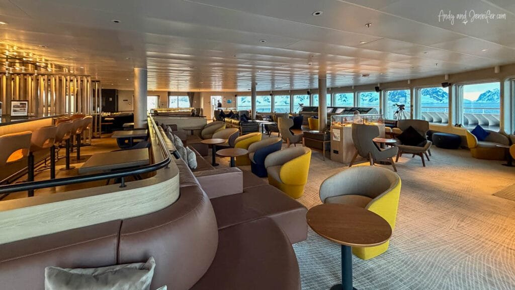 Empty Panorama Lounge aboard the Quark Ultramarine expedition ship with panoramic Antarctic views through large windows near the Lemaire Channel
