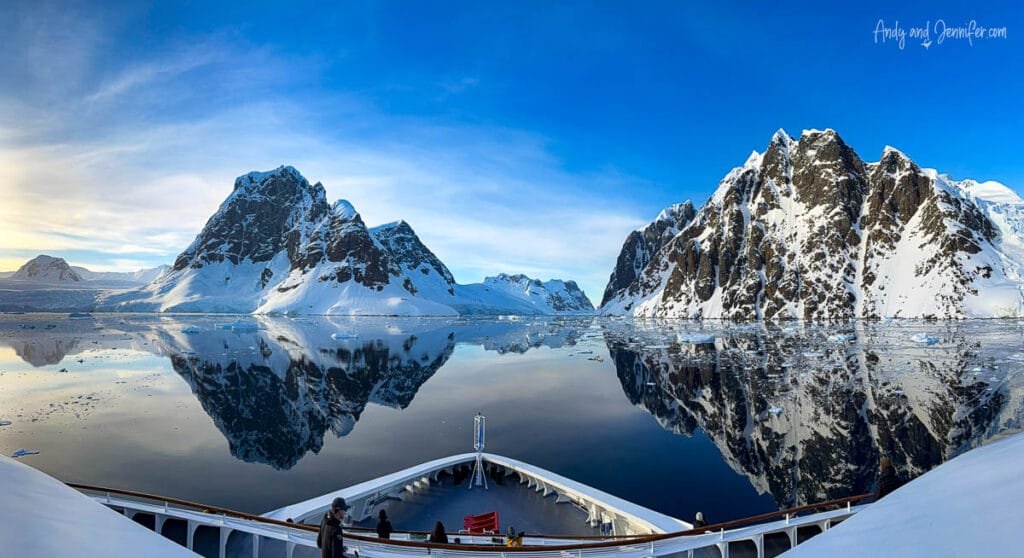 Mirror-like reflections of Antarctic mountains and sea ice viewed from the bow of an expedition ship cruising through the Lemaire Channel in Antarctica