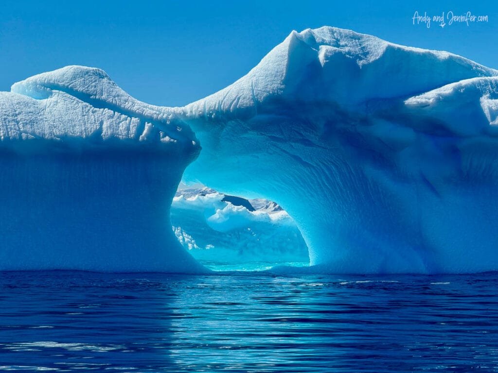 Brilliant blue Antarctic iceberg arch reflected in calm water in Hidden Bay along the Antarctic Peninsula