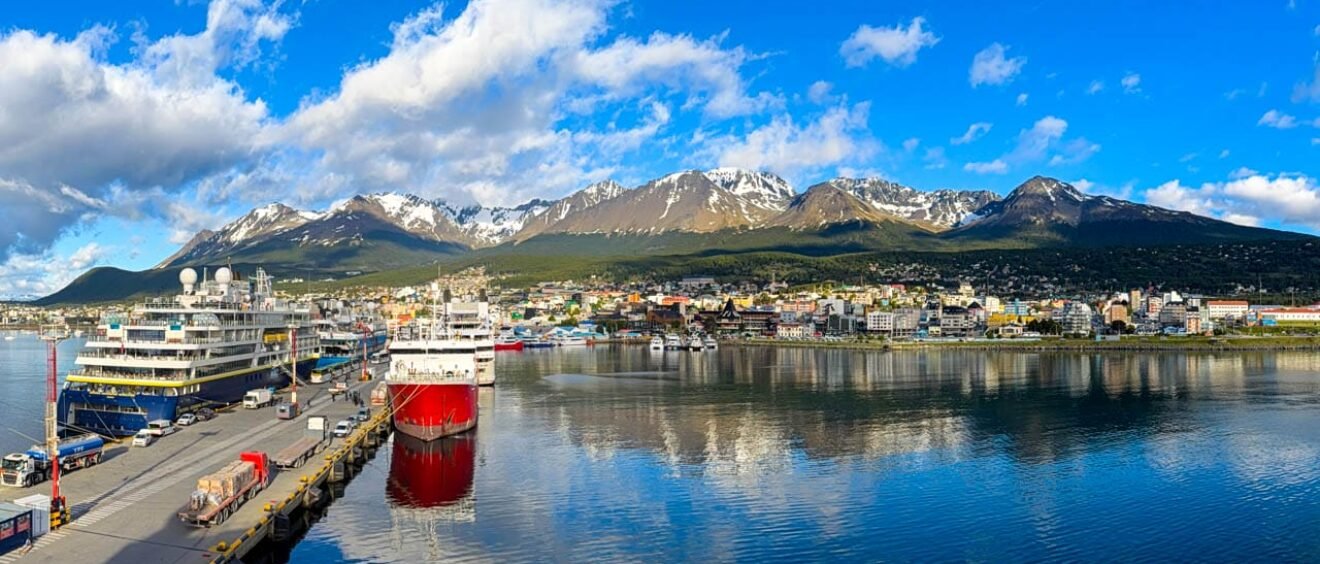 Panoramic view of Ushuaia harbor with expedition cruise ships, calm reflections, and snow-capped mountains in Ushauai, Argentina, after an Antarctica expedition cruise