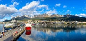 Panoramic view of Ushuaia harbor with expedition cruise ships, calm reflections, and snow-capped mountains in Ushauai, Argentina, after an Antarctica expedition cruise