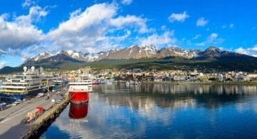 Panoramic view of Ushuaia harbor with expedition cruise ships, calm reflections, and snow-capped mountains in Ushauai, Argentina, after an Antarctica expedition cruise