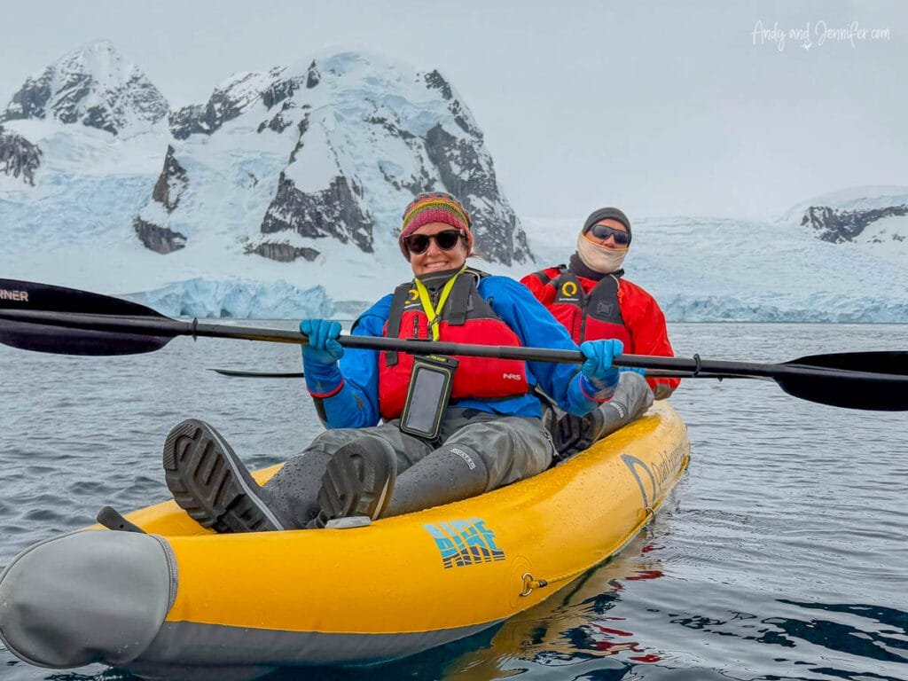 Two people paddling an inflatable kayak in Antarctica near Danco Island with glaciers and snowy Antarctic mountains in the background