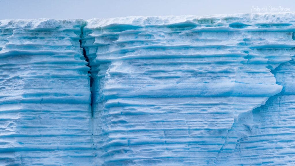 Close-up of layered blue glacial ice with deep crack in Antarctica