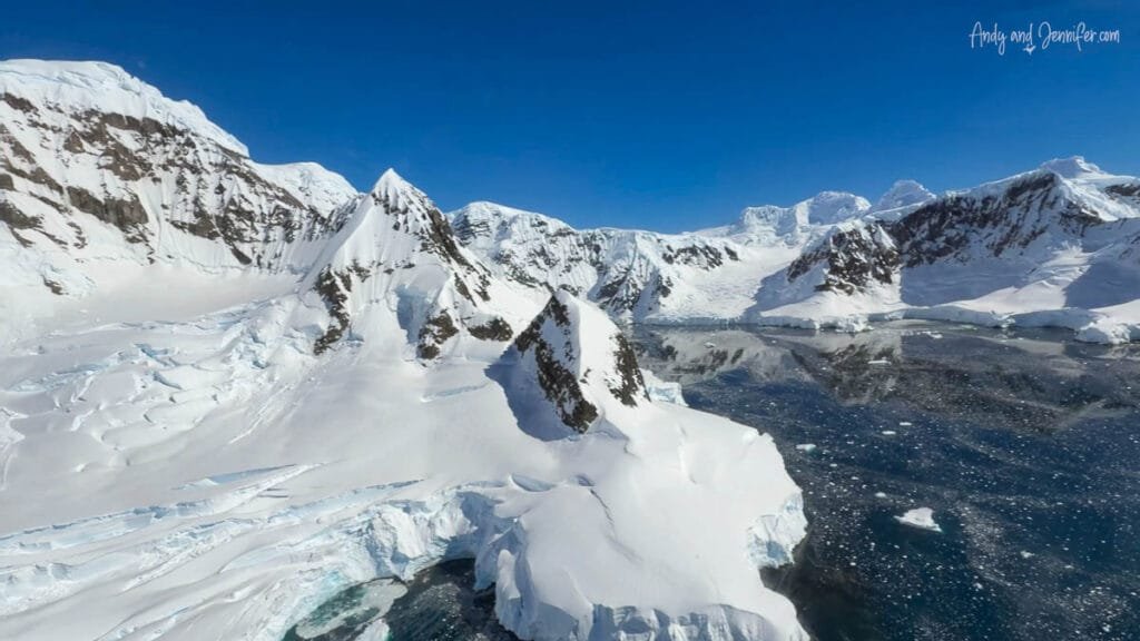 Aerial view of glaciers, snow-covered peaks, and sea ice during a helicopter flightseeing excursion over the Antarctic Peninsula.