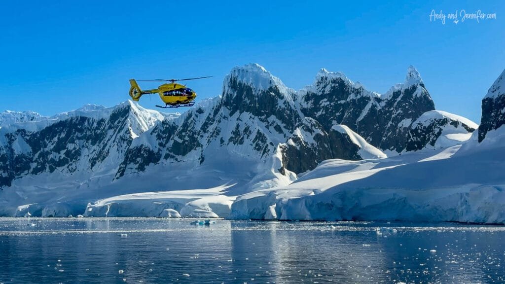 Helicopter flying past snow-covered peaks and glaciers during a flightseeing excursion over the Antarctic Peninsula.