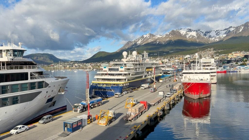 Expedition cruise ships docked in Ushuaia harbor beneath snow-capped mountains at the end of an Antarctica expedition cruise in Argentina