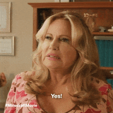 Close-up of Jennifer Coolidge smiling enthusiastically, expressing excitement and approval with text for "yes yes a thousand times yes"
