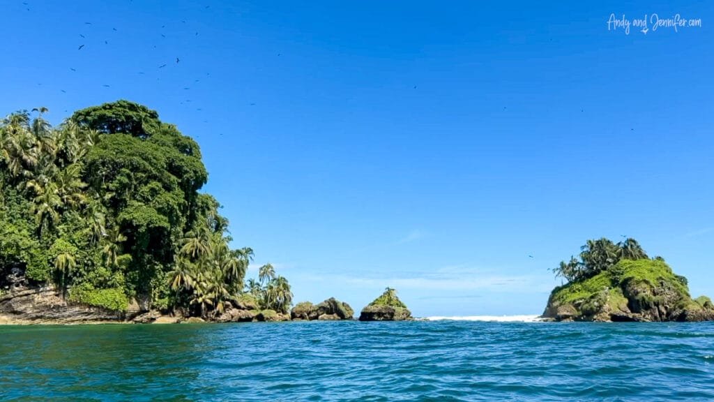 Bird Island off the Caribbean coast of Panama, a small offshore seabird colony surrounded by turquoise water and lush tropical vegetation under a cloudless sky.