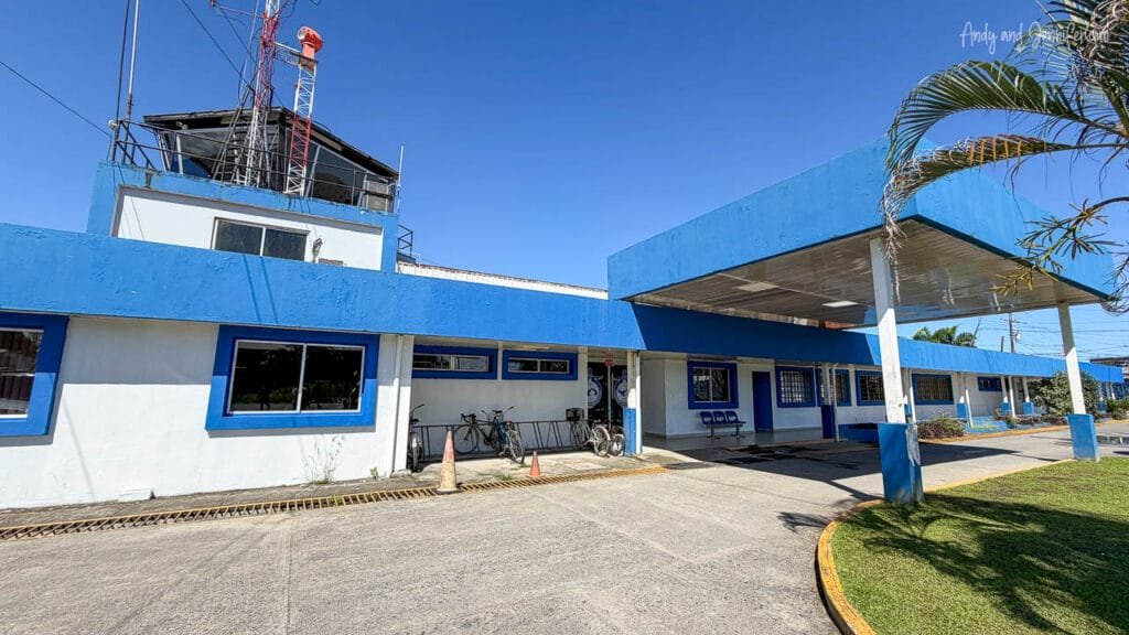 The exterior of Changuinola Airport in Panama, a small regional airport with a blue-and-white terminal building beneath a clear tropical sky.