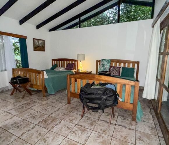 Basic guest room with two wooden beds and large forest-facing windows at Rancho Naturalista in Costa Rica.
